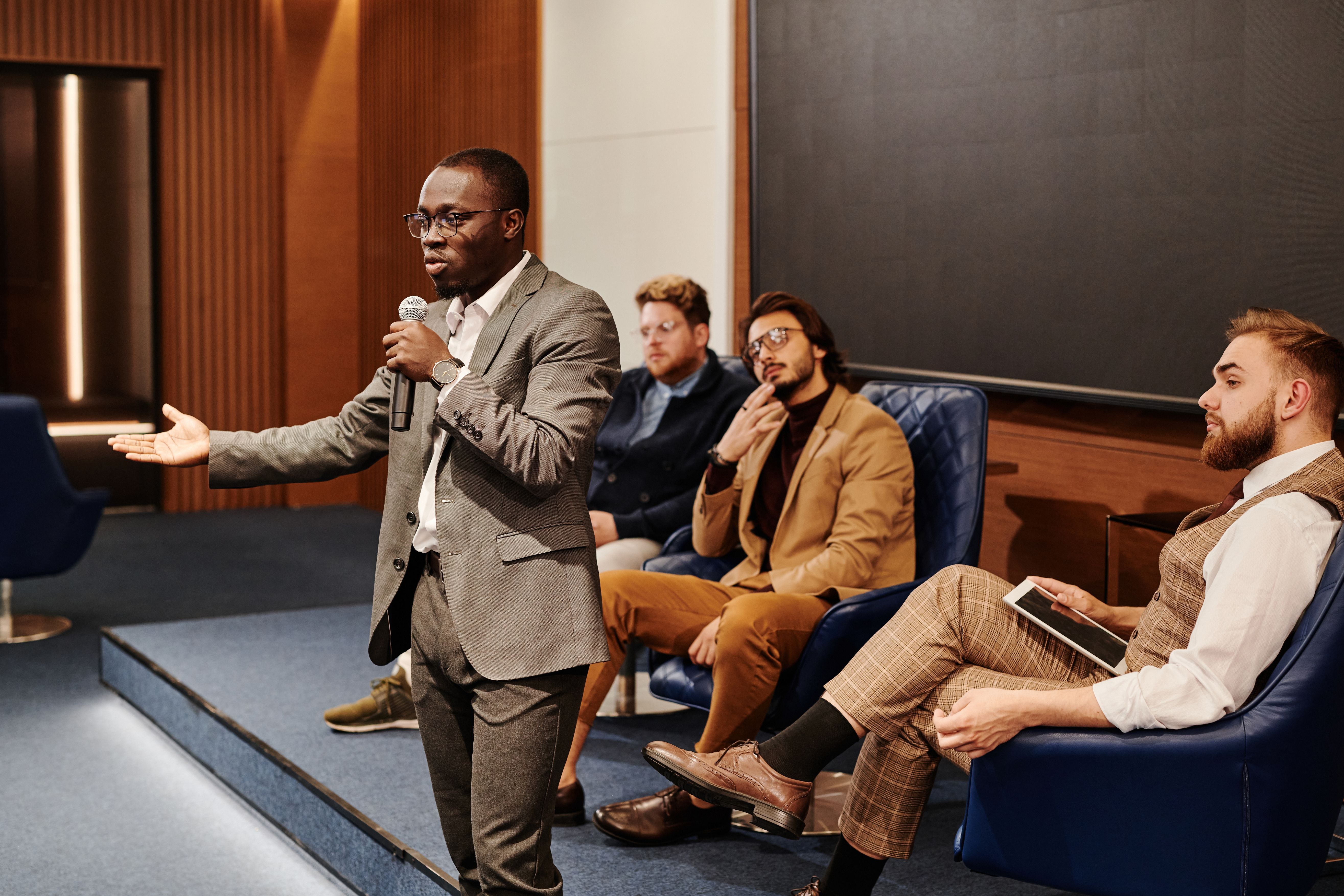 Intervenant au micro devant un panel lors d’une conférence professionnelle