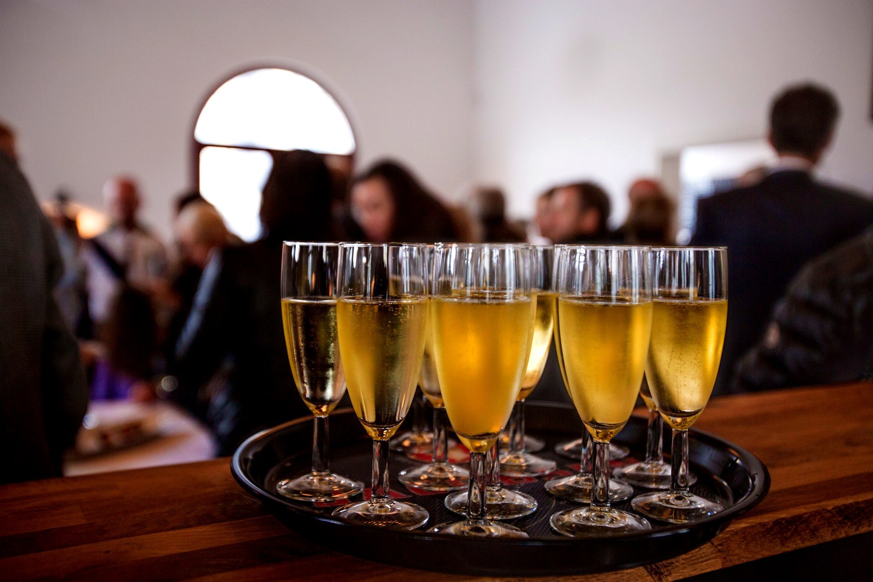 Plateau de flûtes devant des invités réunis lors d'une réception en intérieur